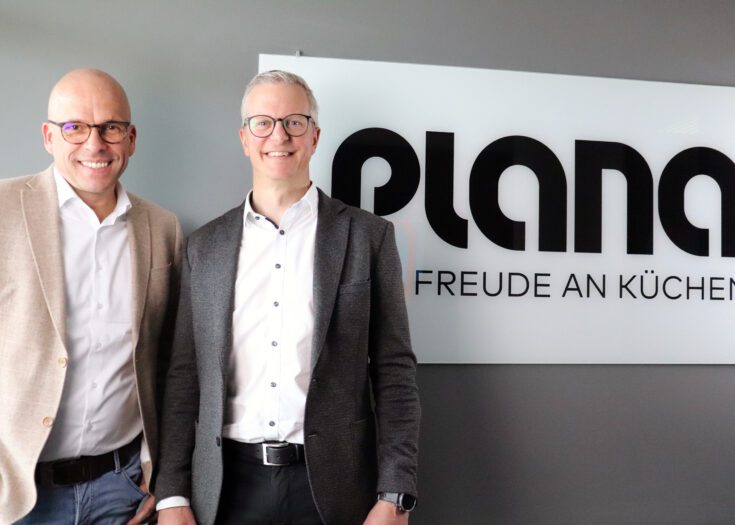 Zwei Männer stehen neben Firmenlogo