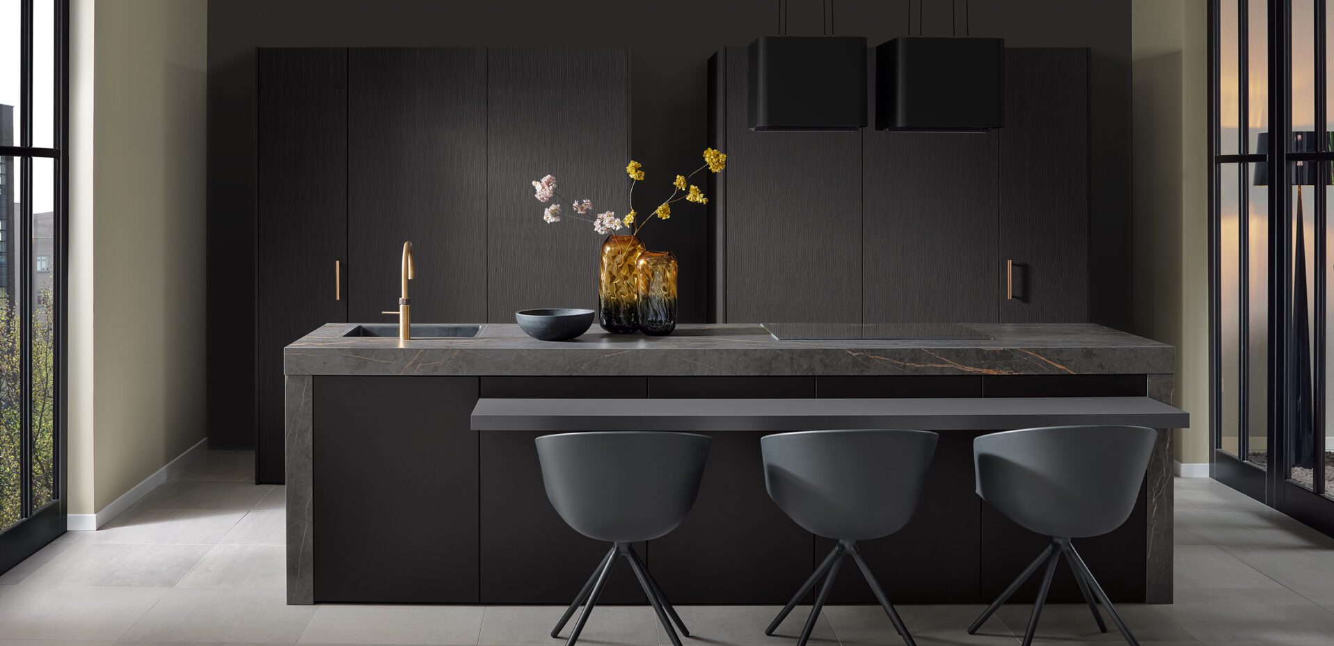 Luxuriöse Kochinsel mit Marmor-Arbeitsplatte und Barhockern vor dunkler Schrankwand.