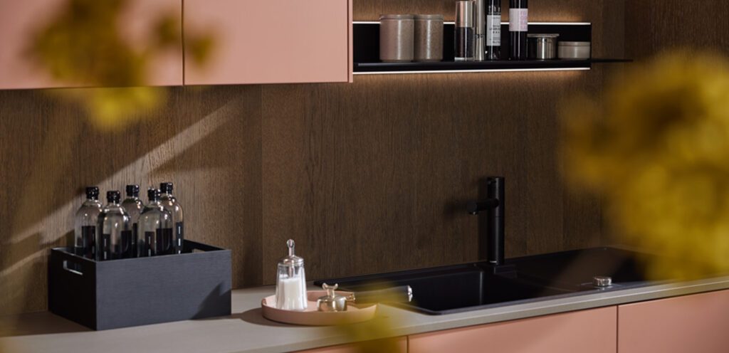 Küchenzeile mit rosanen Fronten und schwarzer Spüle und grauer Arbeitsplatte