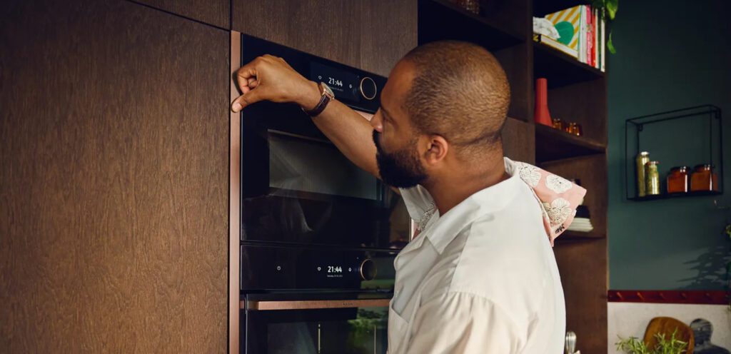 Mann befestigt kupferfarbene Leisten um Neff Einbaugeräte