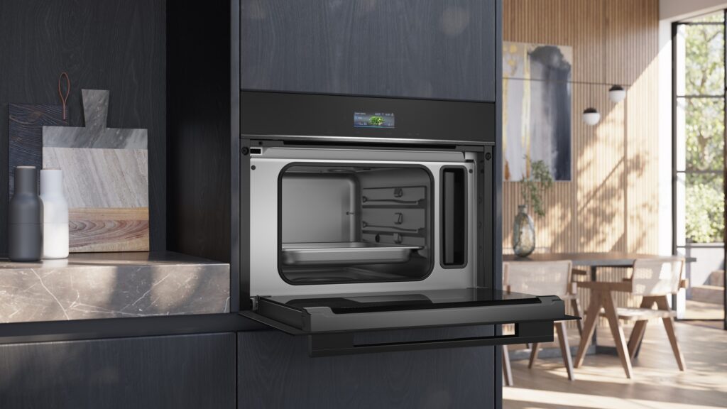 Siemens CD714GXB1 Kompakt-Dampfbackofen, geöffnet, in dunkler Design-Küche integriert.