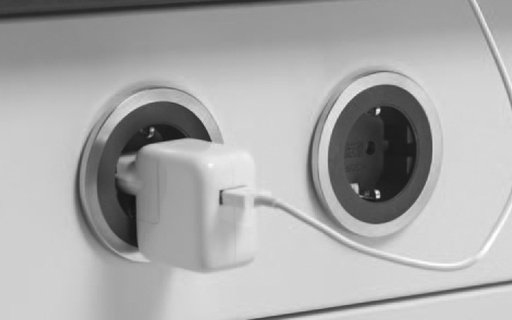In eine runde Steckdose integrierter Adapter mit eingestecktem Ladekabel.
