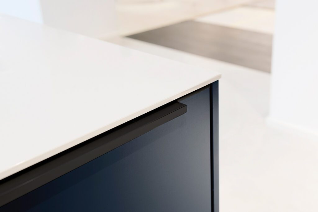 Moderne Küchenfront in Dunkelblau mit aufgesetzter Griffleiste M 745 in Schwarz matt.