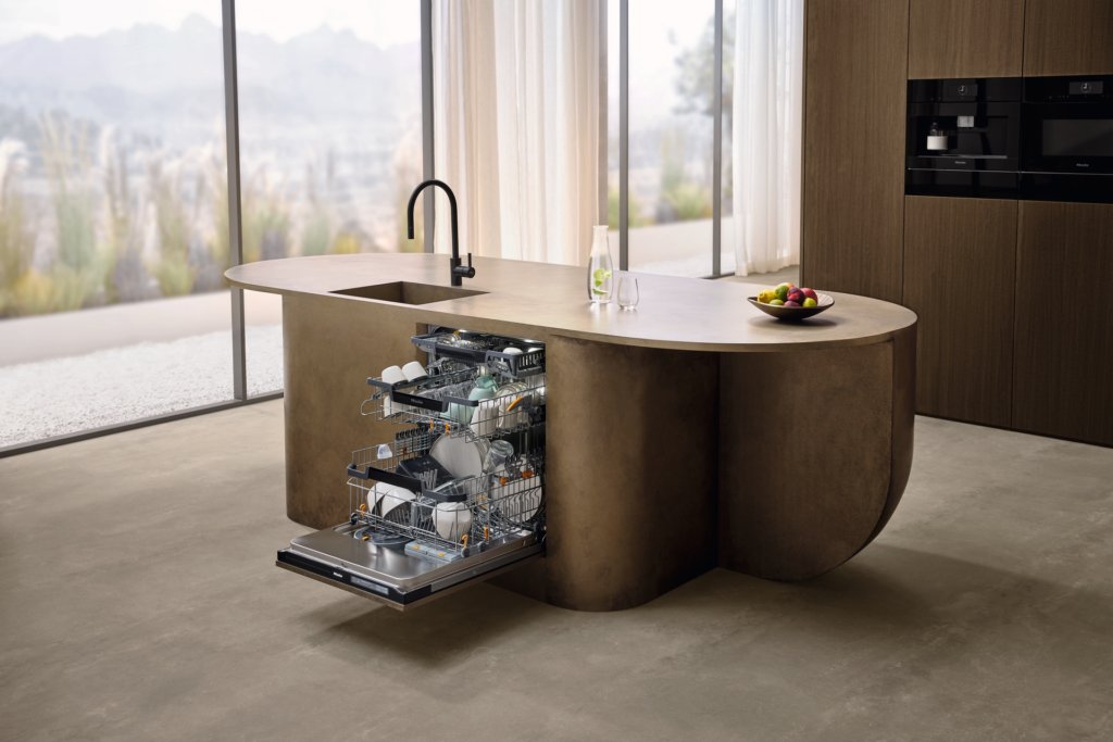 Geöffneter Miele G8000 Geschirrspüler voll beladen in einer organisch geformten, bronze-farbenen Kücheninsel