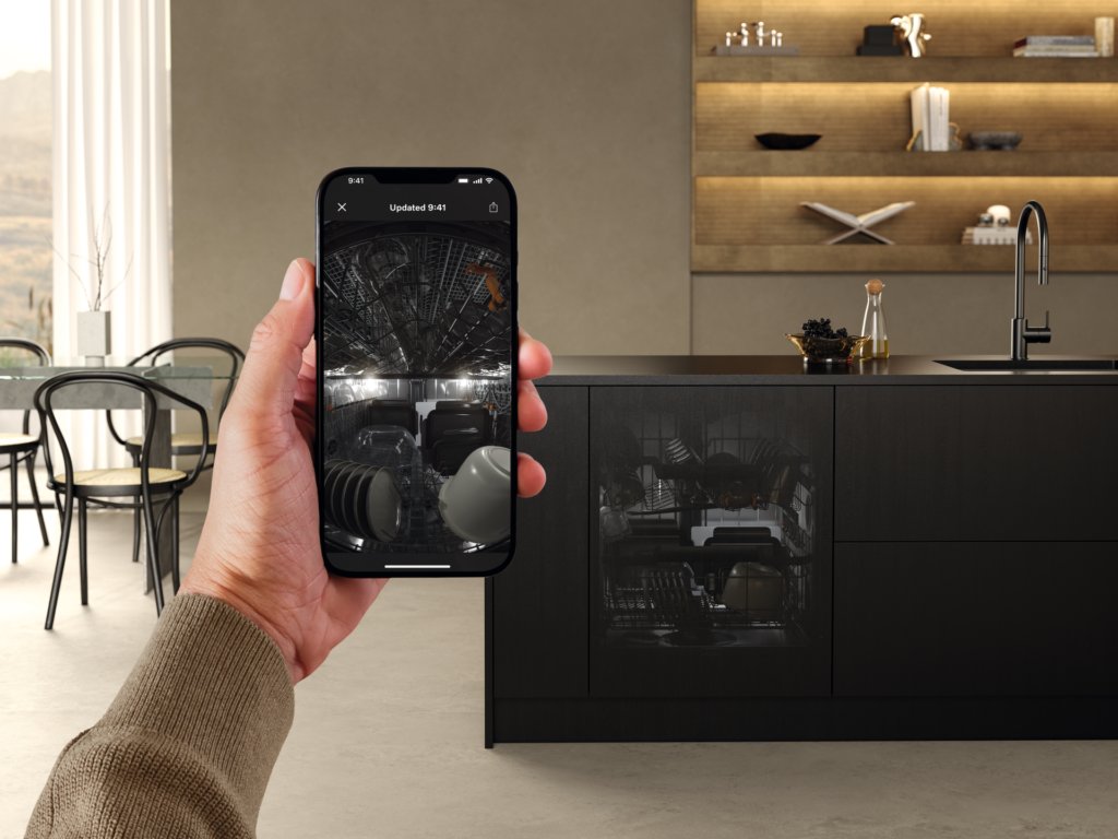 Smartphone zeigt die Innenraumkamera eines Miele Geschirrspülers vor einer schwarzen Kücheninsel